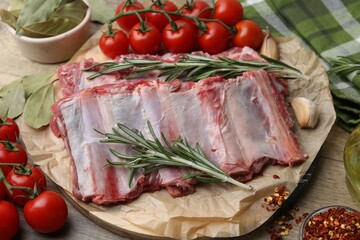 Fresh raw beef ribs, tomatoes and spices on wooden table, closeup