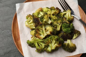 Tasty fried broccoli and fork on black table, top view