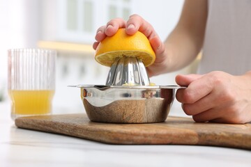 Making juice. Woman with orange using juicer at white marble table indoors, closeup