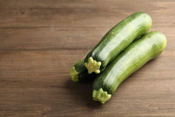 Fresh ripe zucchinis on wooden table, closeup. Space for text