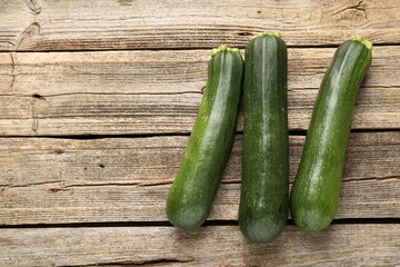 Fresh ripe zucchinis on wooden table, flat lay. Space for text