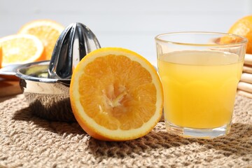 Freshly squeezed orange juice, fruits and juicer on table, closeup