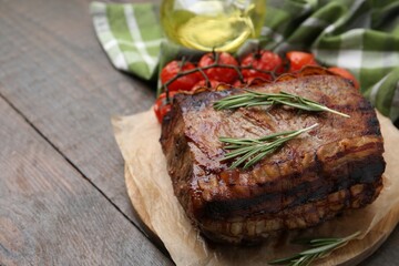 Delicious roast beef with rosemary and tomatoes on wooden table, closeup