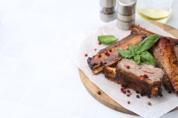 Roasted beef ribs with spices and ketchup on white tiled table, closeup. Space for text