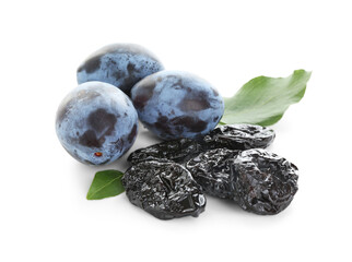 Dried prunes, fresh plums and green leaves isolated on white