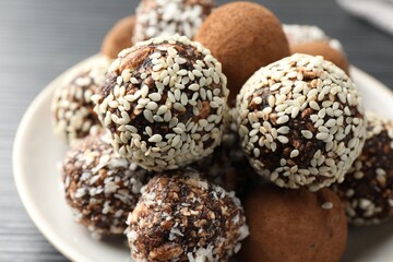 Tasty chocolate candies with cocoa powder, nuts and sesame seeds on table, closeup