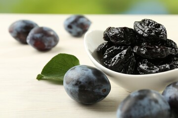 Dried prunes and fresh plums on wooden table, closeup