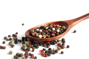 Wooden spoon with different types of peppercorns.	