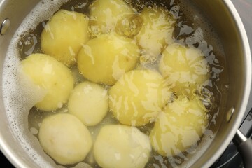 Young potatoes boiling in pot on stove, closeup