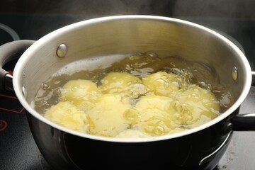 Young potatoes boiling in pot on stove, closeup