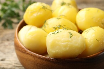 Tasty young boiled potatoes with dill served on wooden table, closeup