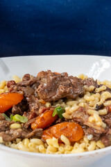 Famous French dish Beef bourguignon with tender pieces of meet, carrots and mushrooms served with cooked pasta in traditional bouillon restaurant in Toulouse, France