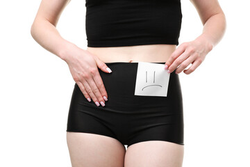 Woman holding sticky note with drawn sad face and suffering from cystitis symptoms on white...