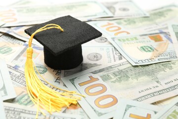 Scholarship. Graduate hat on dollar banknotes, closeup. Space for text