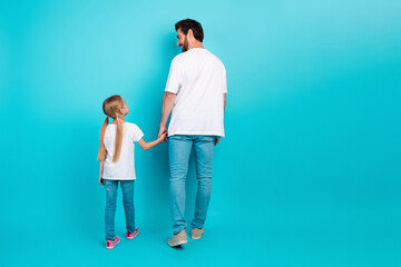 Father holding daughter's hand against teal backdrop emphasizing family bonds and parent-child love