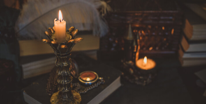 Book and candle on a vintage table, dark academia aesthetic. Evening time