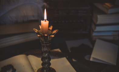 Book and candle on a vintage table, dark academia aesthetic. Evening time
