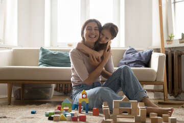 Portrait grateful little girl hug caring mom nanny after playing