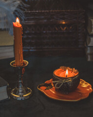 Orange candle on a vintage table, dark academia aesthetic. Evening October time