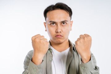 A young man expressing determination with clenched fists against a white background.
