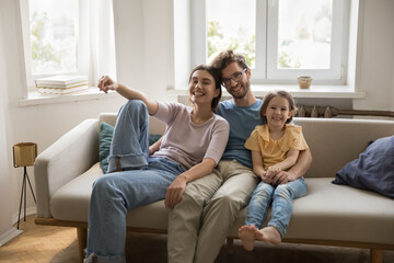 Portrait cheerful bonding couple with kid daughter hugging on sofa