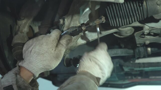 An auto mechanic replaces chassis components. Car suspension repairs.
