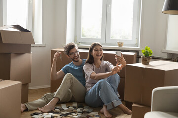 Joyful young spouses take selfie with keys from new apartment
