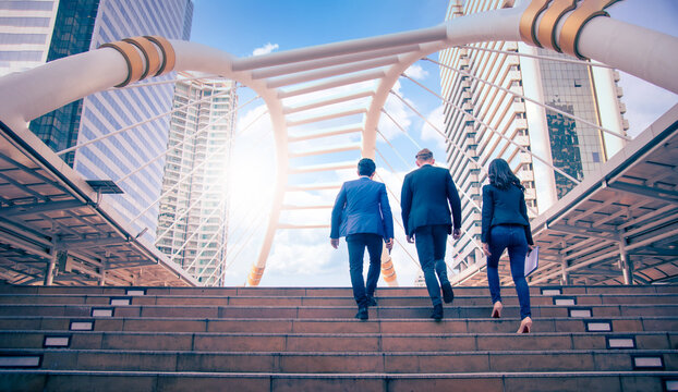 Rear view of business team climbing stairs go to a city at daytime. Business concept - Powered by Adobe