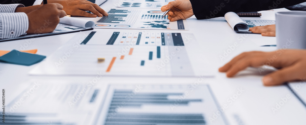 Poster a group of professionals engaged in a business meeting, analyzing charts and graphs displayed on pap