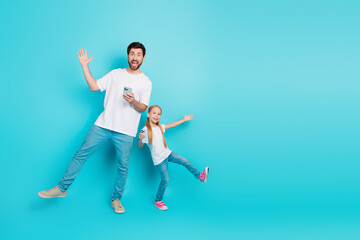 Father and daughter enjoying fun time together holding smartphones on a vibrant blue background, symbolizing joy and connection
