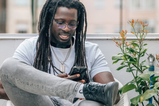 young african man with dreadlocks and mobile phone on the terrace