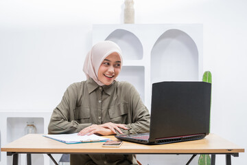 A warm and inviting office environment showcases a woman joyfully engaged with her laptop,