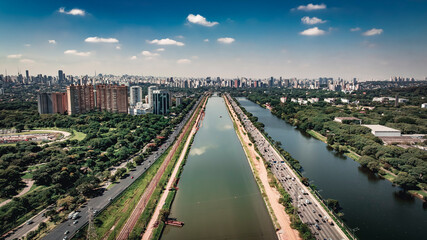 Obraz premium Drone aerial view of São Paulo skyline with Marginal Pinheiros highway, Parque Villa-Lobos green park, USP rowing lane and modern residential buildings on a clear day in Brazil