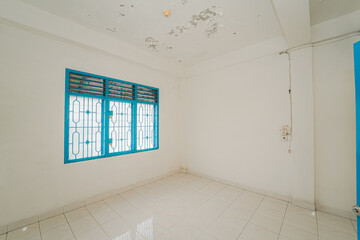 Empty Room with Teal Window and Damaged Ceiling