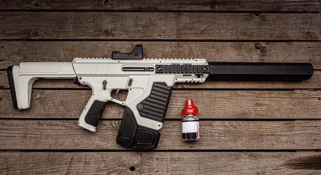 A modern tactical airgun on a wooden background.