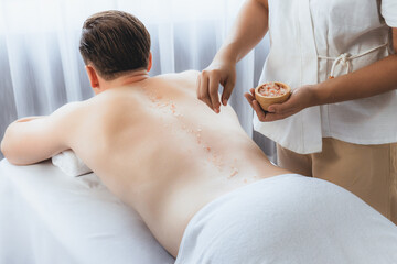 Blissful man customer having exfoliation treatment in luxury spa salon with warmth candle light...