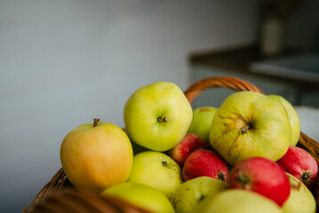 Wicker basket is overflowing with a mix of green, yellow, and red apples and crabapples, suggesting a bountiful harvest and the delights of autumn
