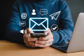 Person holding smartphone with digital communication icons and laptop mobile phone technology