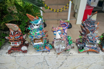 Row of four colorful, hand-painted Shisa statues, traditional Okinawan guardian lion-dogs, sit on a stone wall in Okinawa, Japan. Unique cultural artifacts are believed to ward off evil spirits.