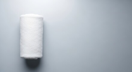 Obraz premium Rolled white towel on gray background - minimalist design