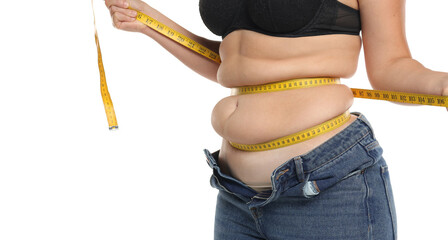 Studio shot of obese woman with belly rolls using measuring tape around waist while jeans stay open...