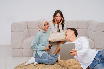Friends are amazed by fascinating content on a tablet while relaxing in a cozy living room