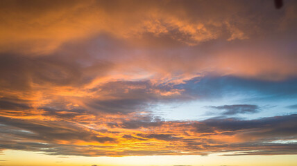 Fototapeta premium Vibrant sunset clouds paint the sky with fiery oranges and soft blues, creating a breathtaking natural spectacle.