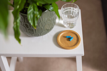 Blue capsule pills with glass of water on the table, lifestyle shot