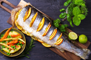 Roasted salmon with lemon, oranges and herbs. View from above, top studio shot