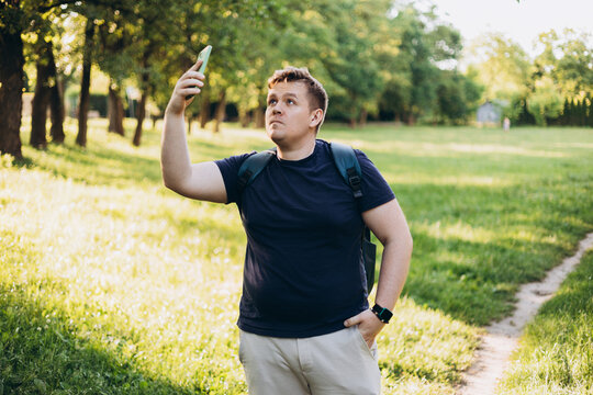 Sad blonde man got lost and could not find an internet connection on phone on the nature background. Male explorer looking for connection to the internet or using gps navigator app on phone