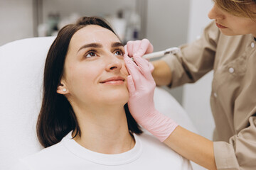 Cosmetologist making markings on woman's face before cosmetic injections