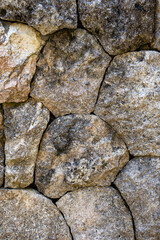 A close-up of a wall made of large, weathered, and multi-colored natural stones, creating an organic and textured background