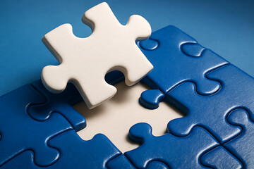 Obraz premium Single white puzzle piece fitting into blue puzzle symbolizing teamwork solution strategy and problem solving concept
