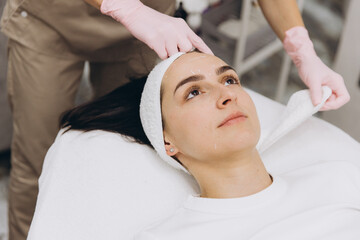 Cosmetologist preparing woman for botox injections by marking face